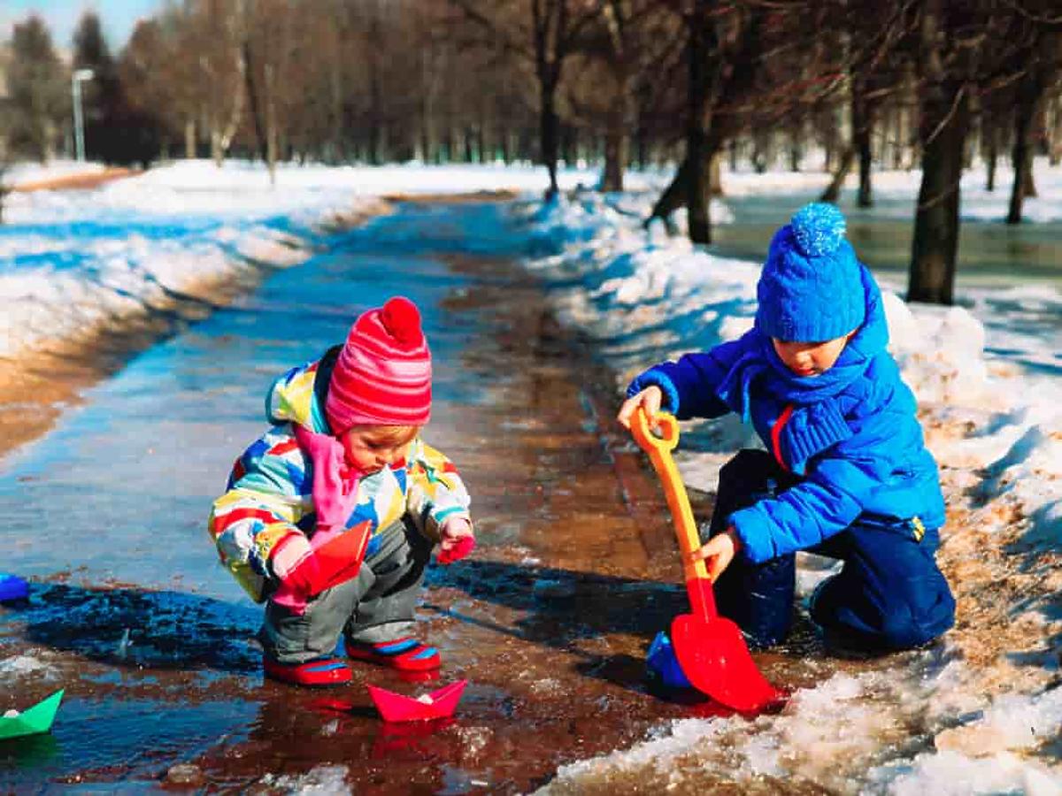 dzieci bawiące się łopatkami w roztapiającym się śniegu